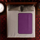 Liberator Fascinator Waterproof Throw Travel Blanket Purple on a neatly made bed with decorative pillows.
