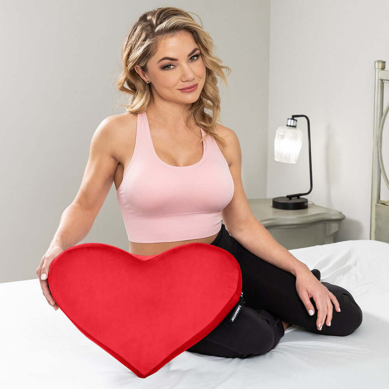 Liberator Heart Wedge Sex Pillow Red displayed with a model in a cozy bedroom setting.