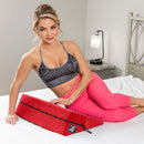 Woman posing with Liberator Wedge Sex Pillow Red on a bed, showcasing comfort and support for intimate moments.