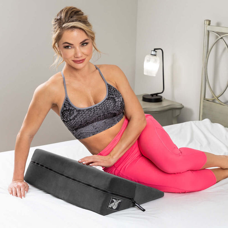 Liberator Wedge Sex Pillow Black in use on a bed by a model in activewear.