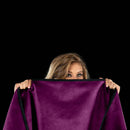 Liberator Fascinator Waterproof Throw Regular Blanket Purple held by a woman, showcasing its plush texture and vibrant color.