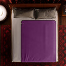 Liberator Fascinator Waterproof Throw Regular Blanket Purple on a bed with pillows.