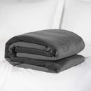 Liberator Fascinator Waterproof Throw Travel Blanket Gray rolled up on a bed.