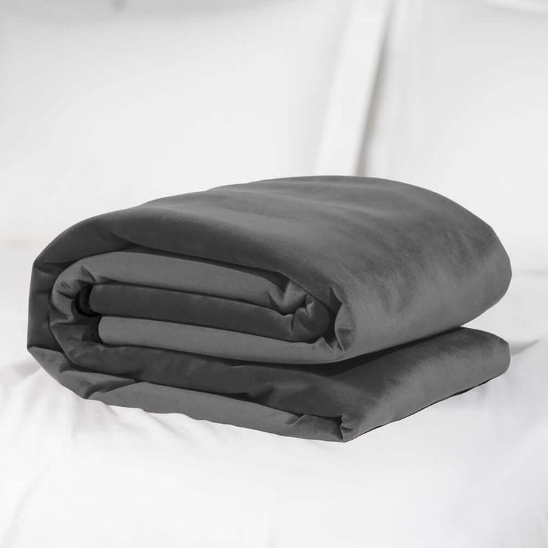 Liberator Fascinator Waterproof Throw Travel Blanket Gray rolled up on a bed.