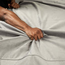 Close-up of a hand gripping the soft texture of the Liberator Fascinator Waterproof Throw Travel Blanket Gray.