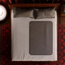 Top view of a bed featuring the Liberator Fascinator Waterproof Throw Travel Blanket Gray on a white sheet.