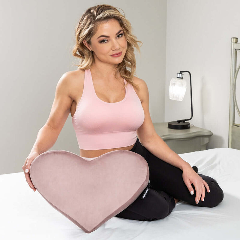 Liberator Heart Wedge Sex Pillow Rose being held by a woman in athletic wear, showcasing its stylish design.