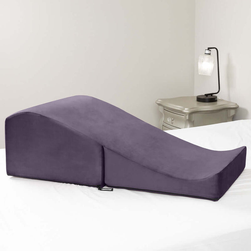 Liberator Flip Ramp Sex Positioning Pillow Plum resting on a bed, designed for enhancing intimate experiences.
