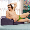Liberator Flip Ramp Sex Positioning Pillow Plum in use by a muscular man lounging casually on the bed.