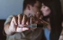 Eye Of Love Bloom Attract Her Pheromone Parfum Blue Ember in hand, romantic couple in the background.