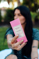 Eye Of Love Bloom Attract Him Pheromone Parfum Sunny Daze in pink box held outdoors.