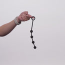 Nexus Excite Silicone Anal Beads Small Black held by hand, showcasing smooth beads and ergonomic design.