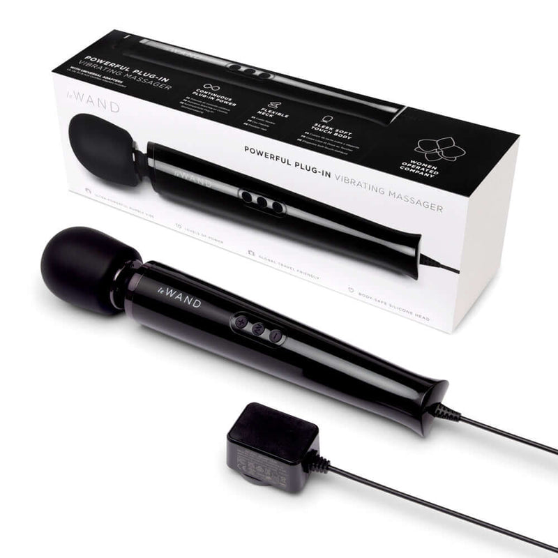 Le Wand Plug-In Vibrating Massager Black displayed with its packaging and power adapter.