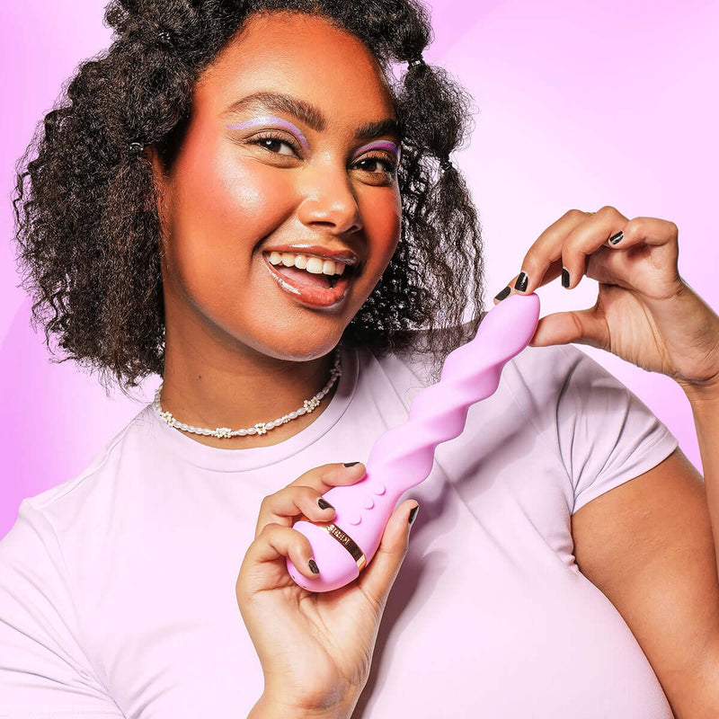 VUSH Siren Twist Vibrator held by a smiling woman with curly hair, showcasing its unique design and vibrant color.