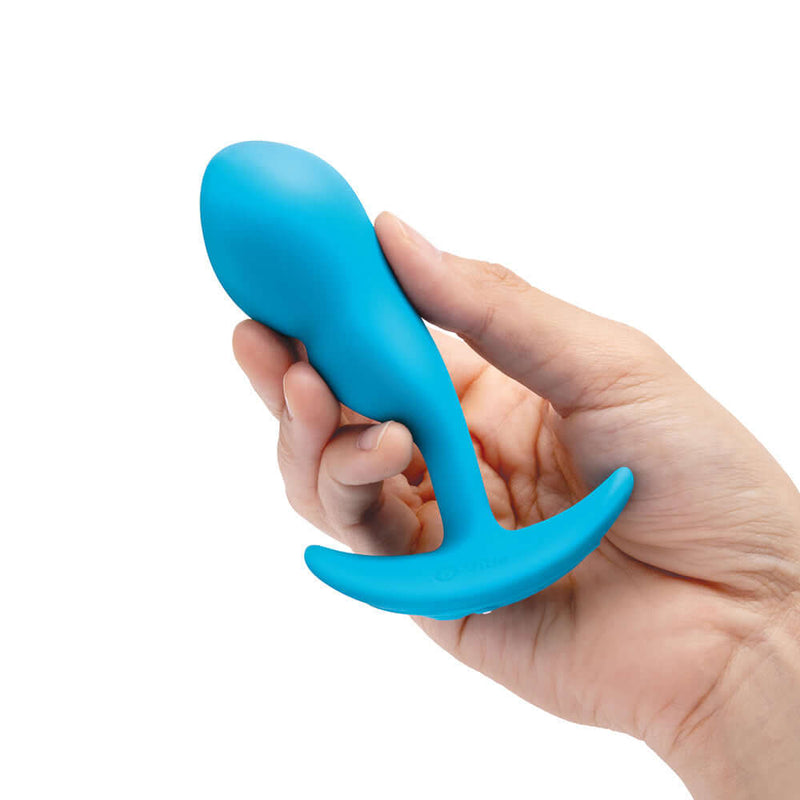 Hand holding the b-Vibe Vibrating P-Spot Snug Plug Small with Remote Control in blue color.