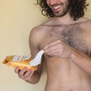 Sweetums Intimate Wipes Peach Scent Unflavored 30 Pack held by a man with curly hair, ready for use.