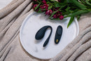 We-Vibe Play Your Way Collection Wearable Vibrator Set Black on a white plate surrounded by flowers and a cozy blanket.