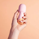 VUSH Peachy Collection Mini Wand held in hand against a peach background, showcasing compact design and features.