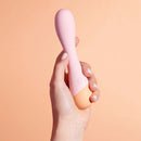 VUSH Peachy Collection G Spot Vibrator held in hand against a peach background, highlighting its sleek design.
