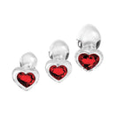 Adam & Eve Red Heart Gem Glass Plug Set featuring three graduated glass plugs with heart-shaped red gem bases.