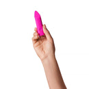 A hand holding the Dame Zig Lipstick Vibrator Pink, showcasing its sleek and compact design.