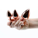 Adam & Eve Rose Gold Pink Heart Anal Plug Training Set held in hand, showcasing elegant design and graduated sizes.