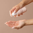 Hands dispensing Playground Mood Maker Body & Massage Oil into palm, showcasing its silky texture.