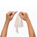 Hands holding a round cotton pad and a white cloth, demonstrating use of the Beloved Freshen Up Travel Kit.