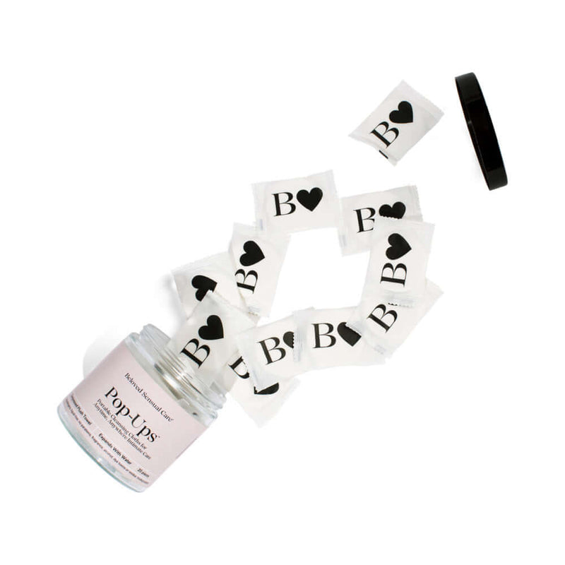 Beloved Pop-Up Cleansing Cloths in a jar with cloths spilling out, perfect for on-the-go freshness and cleanliness.
