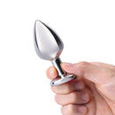 b-Vibe Jewel Metal Training Plug Set held in hand, featuring a sleek and shiny metal design with a comfortable grip.