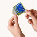 Dame Ultra Thin Condoms 3-Pack packaging being held with a condom partially visible, showcasing its ultra-thin design.