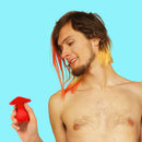 Cute Little Fuckers Morrie Mushroom Vibrator Red held by a smiling person with colorful hair, set against a bright blue background.