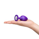 b-Vibe Jewel Butties Bundle purple silicone anal plug held in hand with jeweled base for stylish comfort.