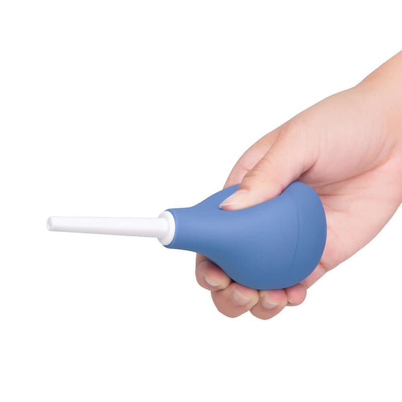 b-Vibe Compact Enema Douche Blue held in hand for convenient and discreet cleansing.
