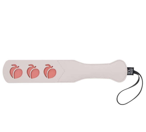 Peaches 'n CreaMe Peach Paddle by Sex&Mischief with peach-shaped cutouts, faux leather design, and wrist strap for playful spanking fun