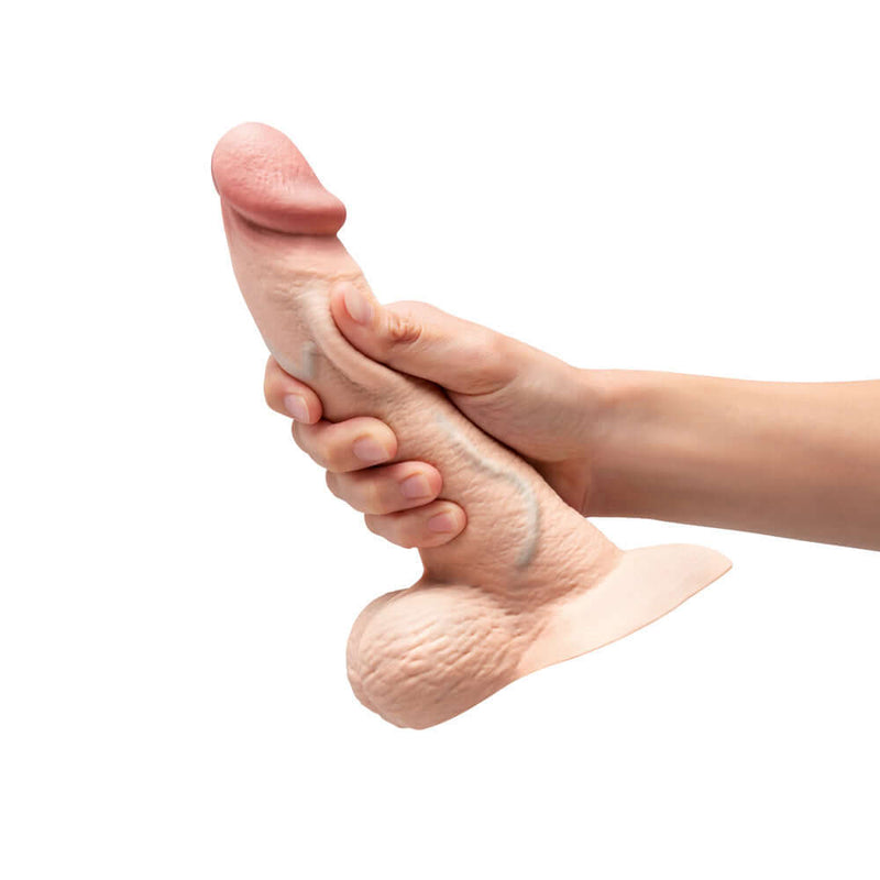 b-Vibe Slipskin Realistic Silicone Dildo 8 inch Curved Cream held in hand, showcasing lifelike texture.