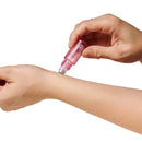 Applying Eye Of Love Pheromone Roll-On Set Sunny Daze Lilac Dream fragrance on wrist with rollerball.