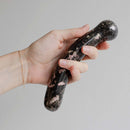 Chakrubs Anahata Curve Rhodonite Wand held in hand for heart chakra healing and emotional balance.