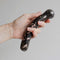 Chakrubs Anahata Curve Rhodonite Wand held in hand for heart chakra healing and emotional balance.
