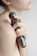 A woman holding the Chakrubs Anahata Curve Rhodonite Wand against her shoulder, showcasing its design and texture.