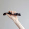 Hand holding the Chakrubs Xaga Viper Obsidian Wand, showcasing its ridged and sleek design.