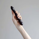 Person holding the Chakrubs Xaga Viper Obsidian Wand, showcasing its hand-carved design and unique curves.
