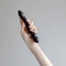 Person holding the Chakrubs Xaga Viper Obsidian Wand, showcasing its hand-carved design and unique curves.
