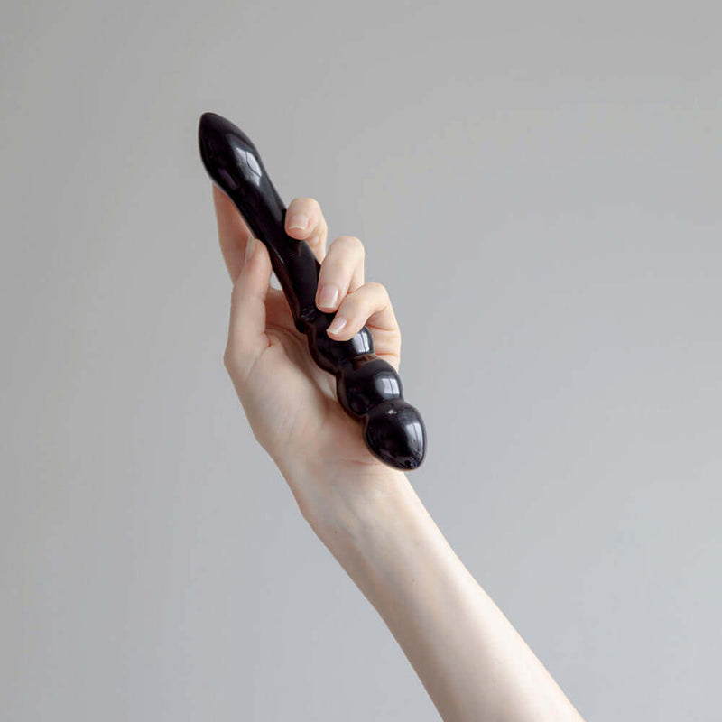 Person holding the Chakrubs Xaga Viper Obsidian Wand, showcasing its hand-carved design and unique curves.