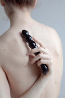 Chakrubs Xaga Viper Obsidian Wand held on bare back for pleasure and relaxation.