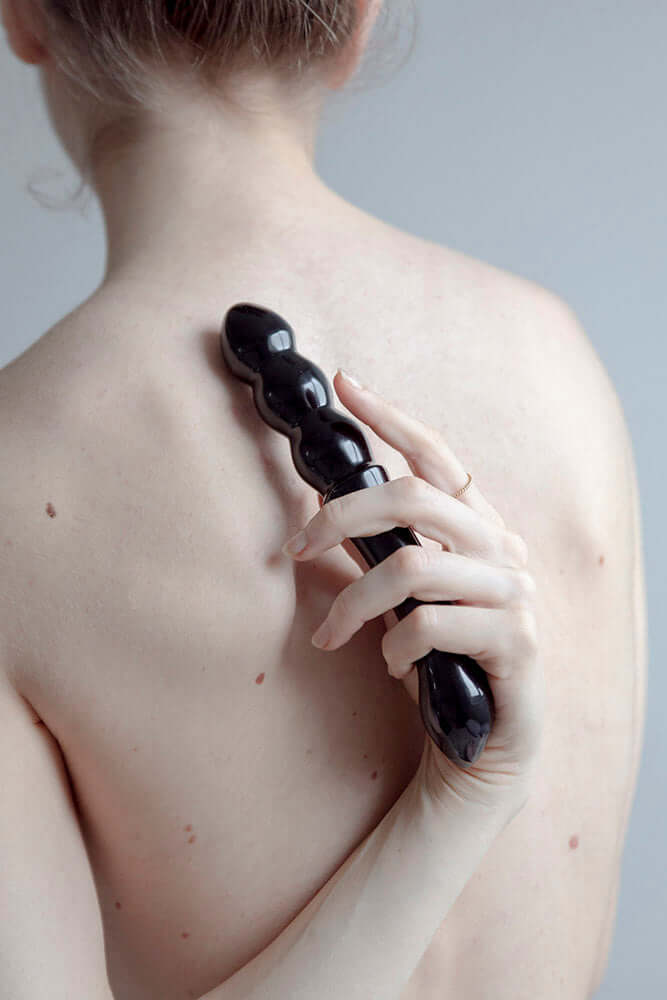 Chakrubs Xaga Viper Obsidian Wand held on bare back for pleasure and relaxation.