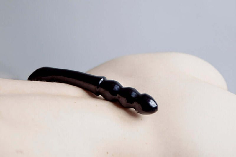 Chakrubs Xaga Viper Obsidian Wand resting on a smooth surface, highlighting its sleek and curvy design.