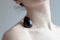 Chakrubs Xaga Yoni Egg Obsidian non-drilled resting on a model's shoulder, showcasing its smooth black surface.