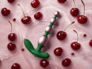 FemmeFunn Bougie Beads Rose Gold alongside fresh cherries on a pink surface, highlighting elegance and indulgence.