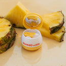 Sweetums Flavored Lip Balm Pineapple in a tropical setting with pineapple slices.